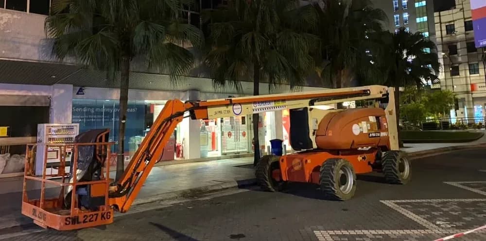 A JLG 800AJ articulated boom lift rental unit working in a city.