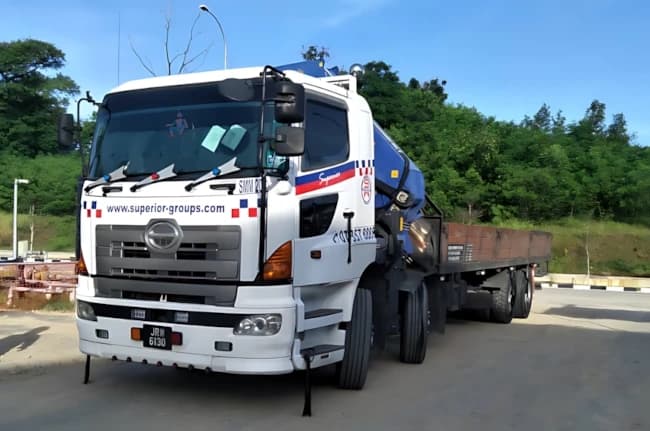 A white lorry truck with a folded Palfinger PM knuckle boom crane.