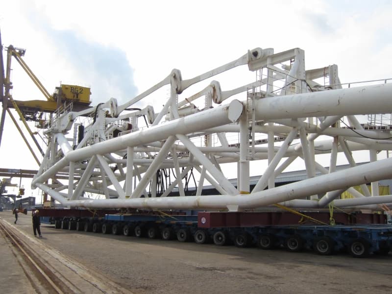 Multi-axle modular trailer transporting a large industrial structure.