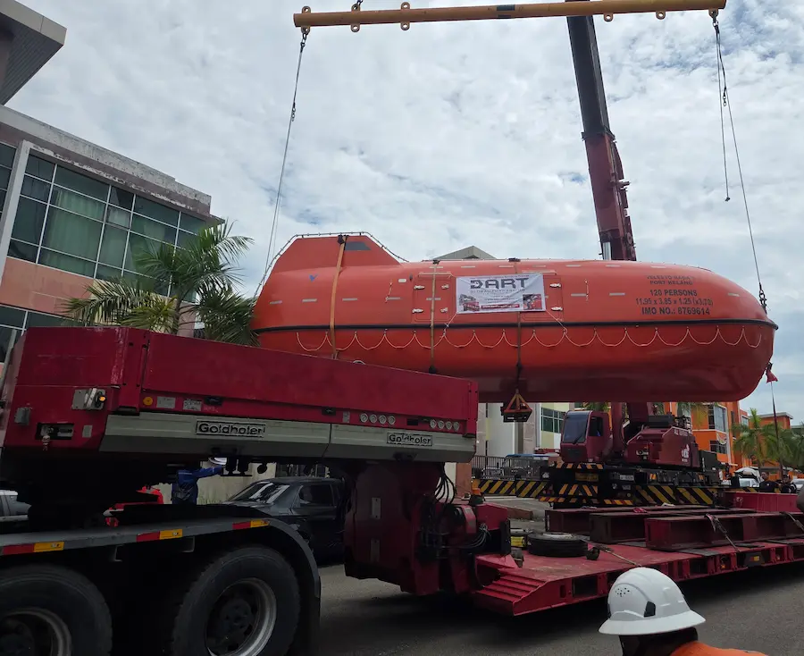 Precision loading of the lifeboat onto a super low deck trailer for transport across Malaysia.
