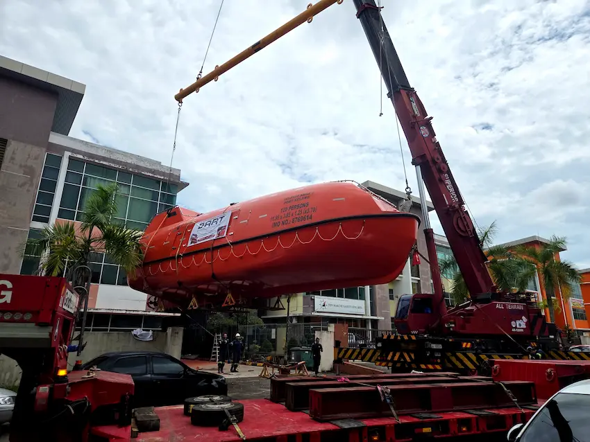 Specialized rigging and soft slings applied to protect the sensitive fiberglass hull of the lifeboat.