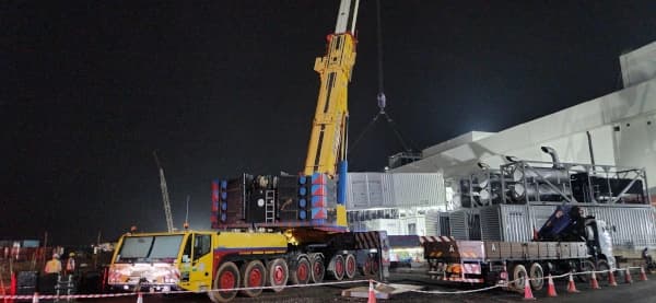 Expert riggers guiding a backup generator during the precision lift.