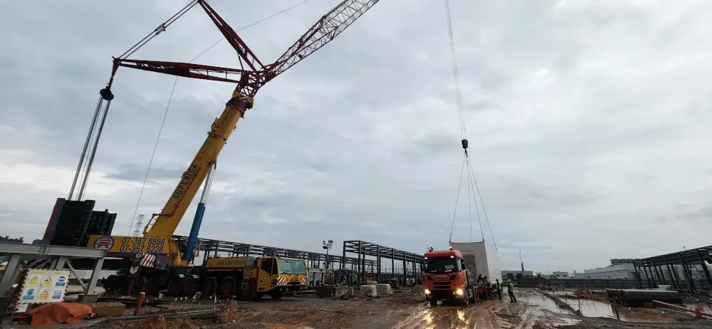 Ground crew supervising the precise placement of a heavy module.