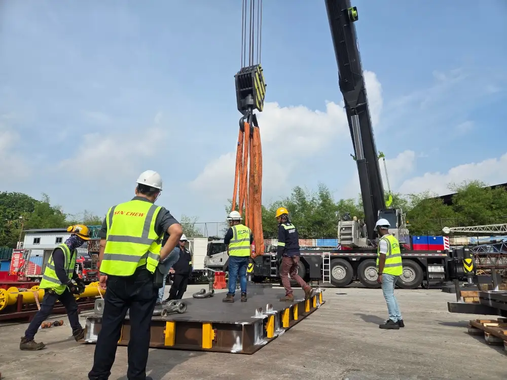 A custom-fabricated spreader beam undergoing a load test by lifting a heavy industrial component.