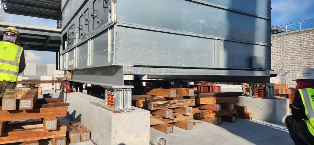 Expert riggers guiding the 26-ton cooling equipment during installation.